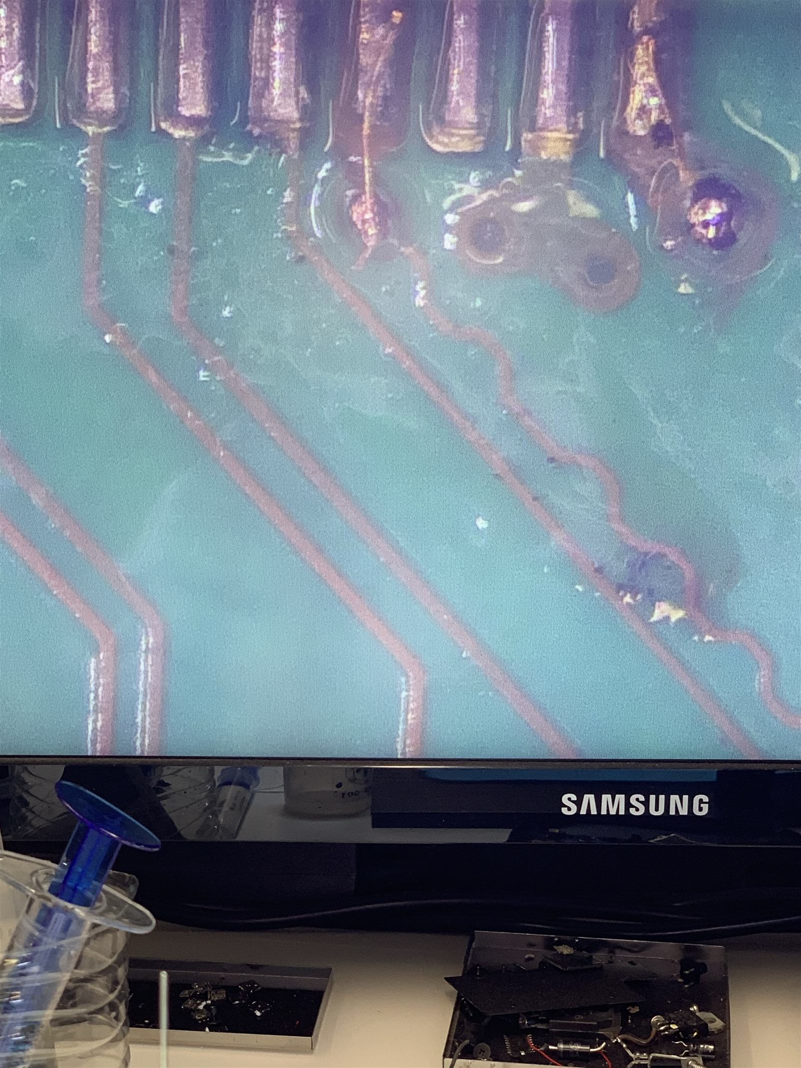 Close-up microscope view of ultra-fine bonding wire soldered to a torn HDMI pad, far thinner than a human hair