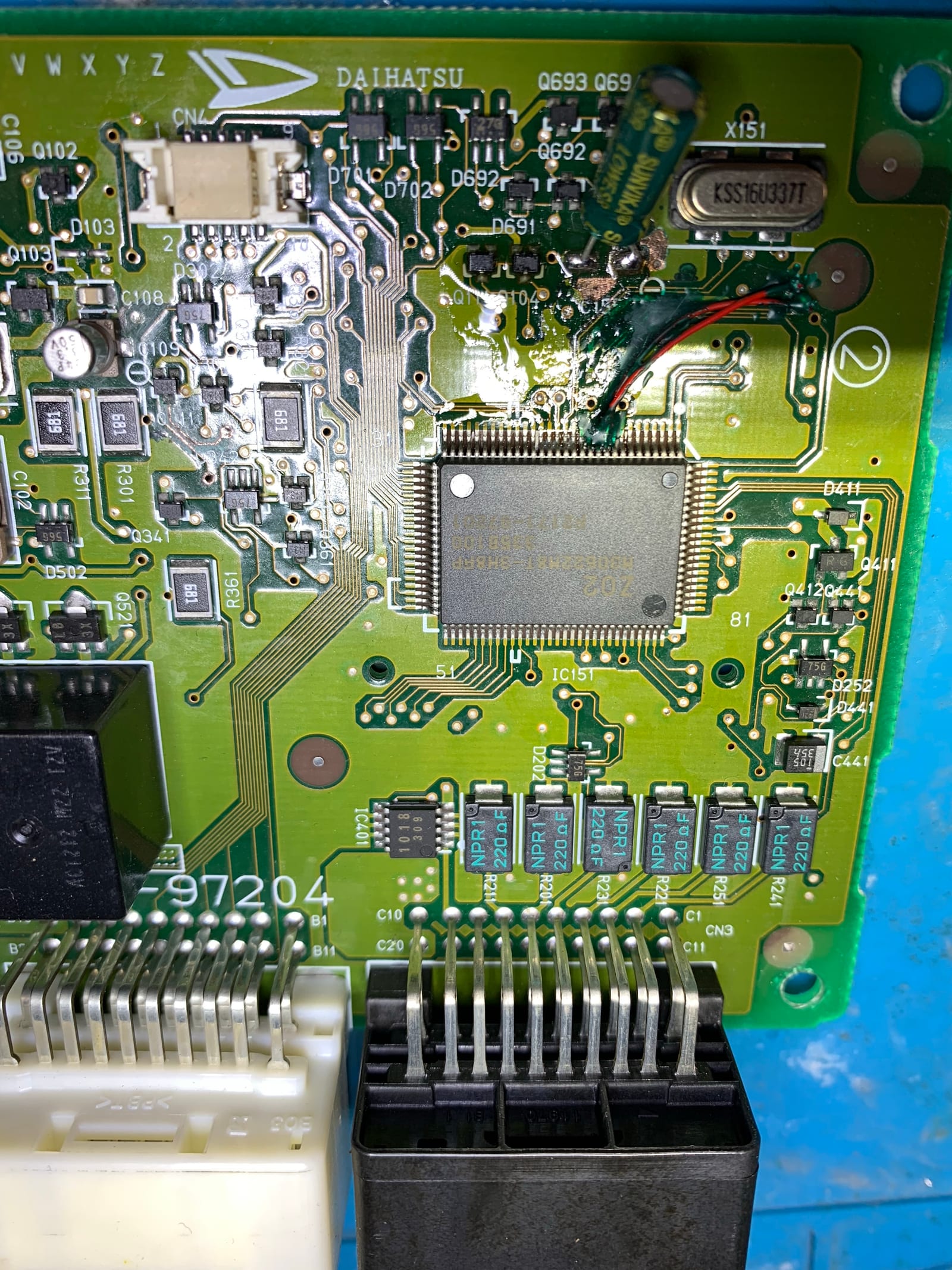 Completed ECU repair showing fine wire reconstruction at the MCU legs sealed under green UV-cure conformal coating