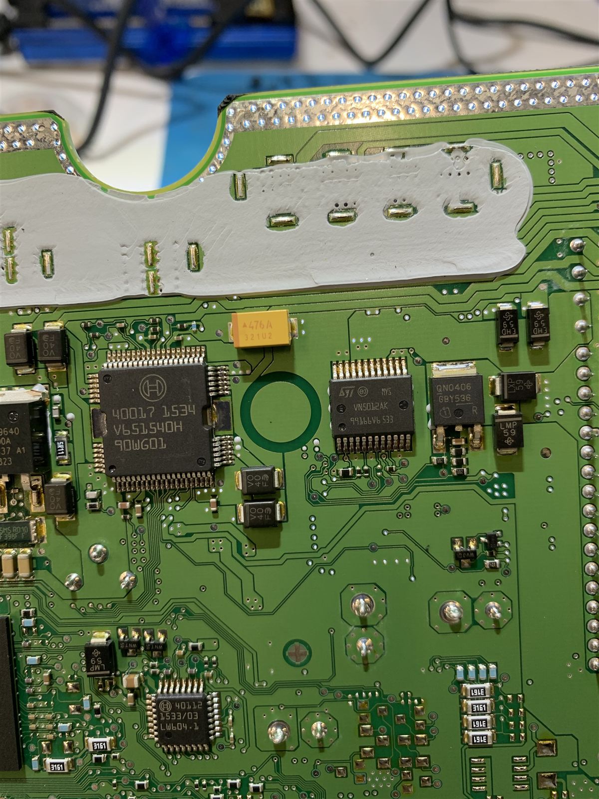 Close view of the Bosch ECU board showing the ST VN5012AK chip next to a QN0406 power MOSFET, below the grey thermal compound