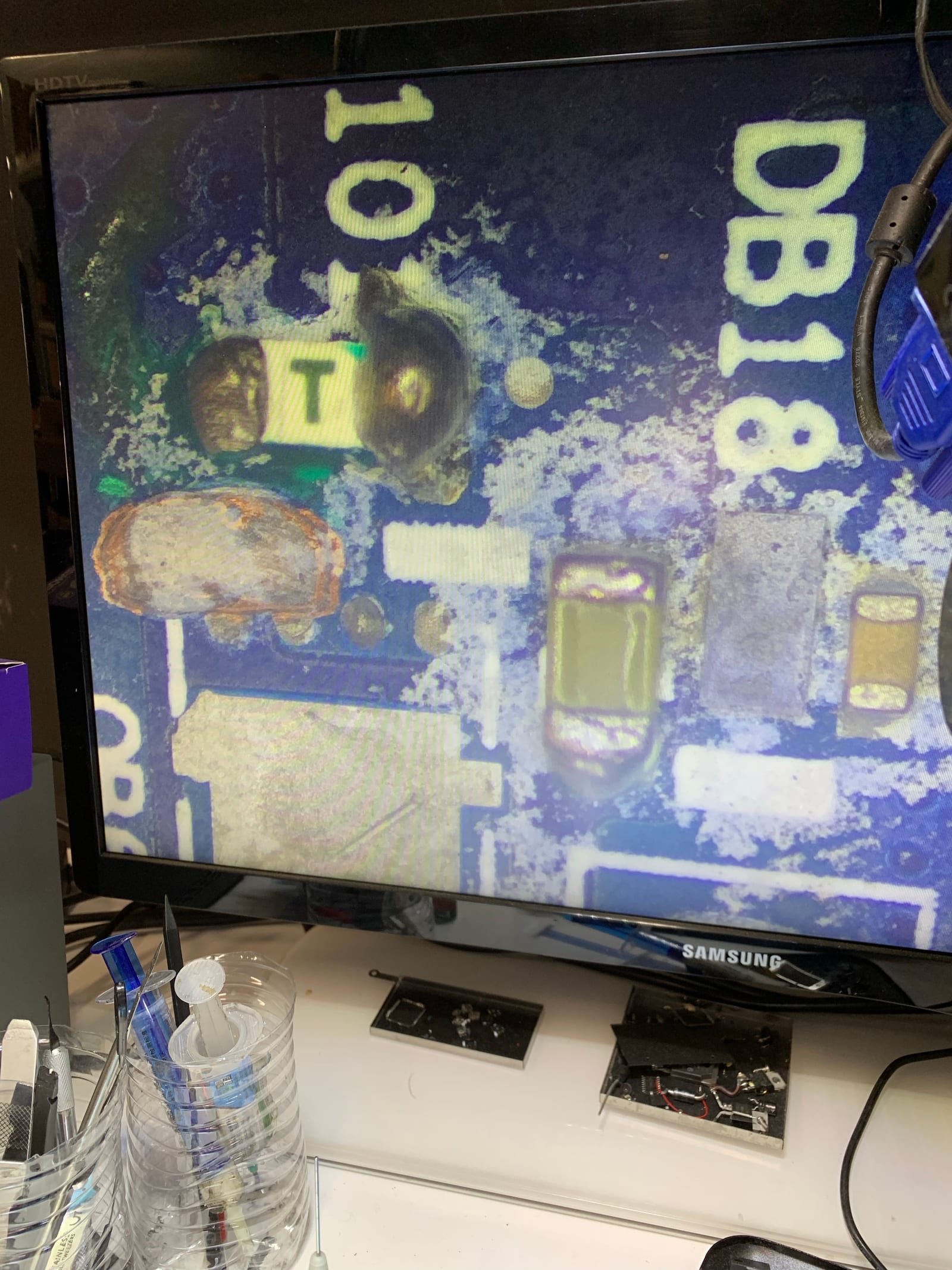 Microscope camera view on a bench monitor showing the Lenovo motherboard's power section near the DB18 marking, with the suspect load-switch MOSFET labelled for testing