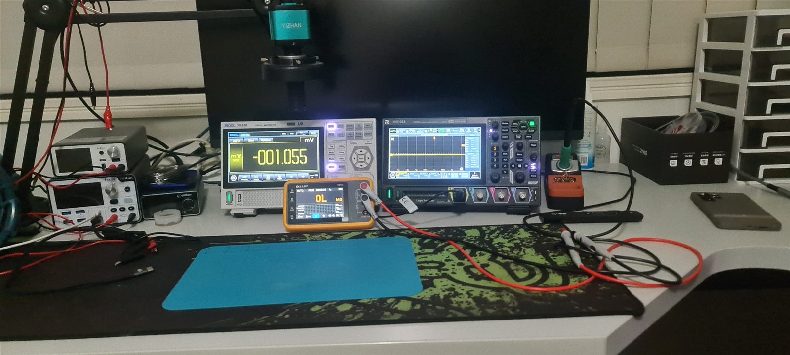 CQ Electronics workshop bench with a Rigol digital multimeter, a mixed-signal oscilloscope with logic analyser channels, an insulation resistance tester, adjustable bench power supplies and a microscope camera